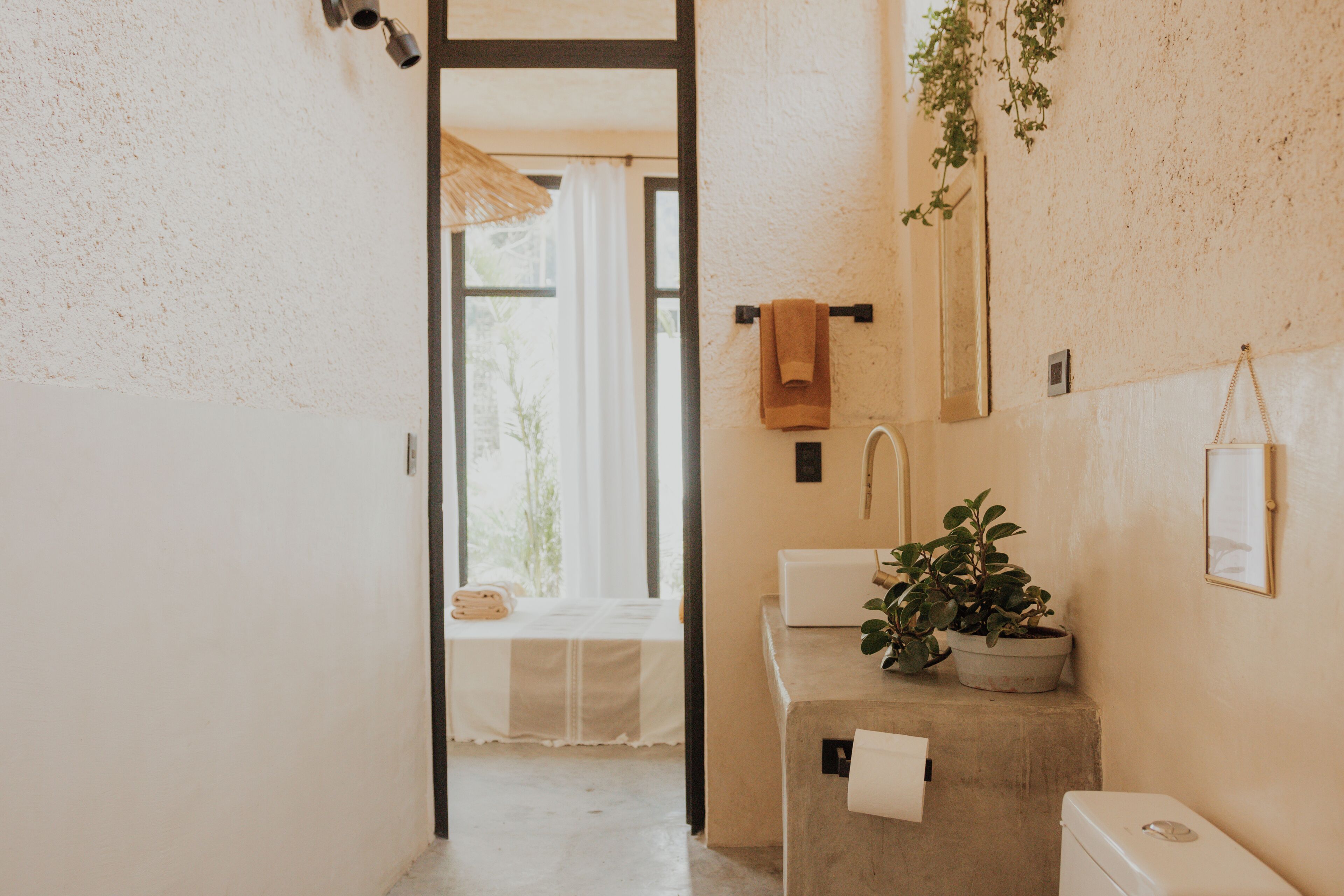 A bathroom with a sink, toilet, and a window with a view of greenery.