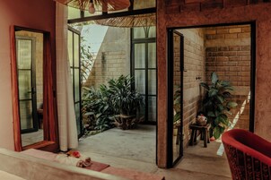 Una habitación con pared de ladrillo, una ventana y una planta.