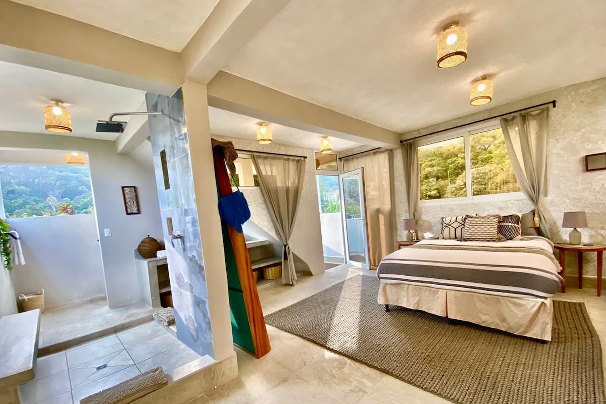 Ein geräumiges Schlafzimmer mit einem großen Bett, einem Balkon mit Aussicht und einer Schiebetür zum Badezimmer.
