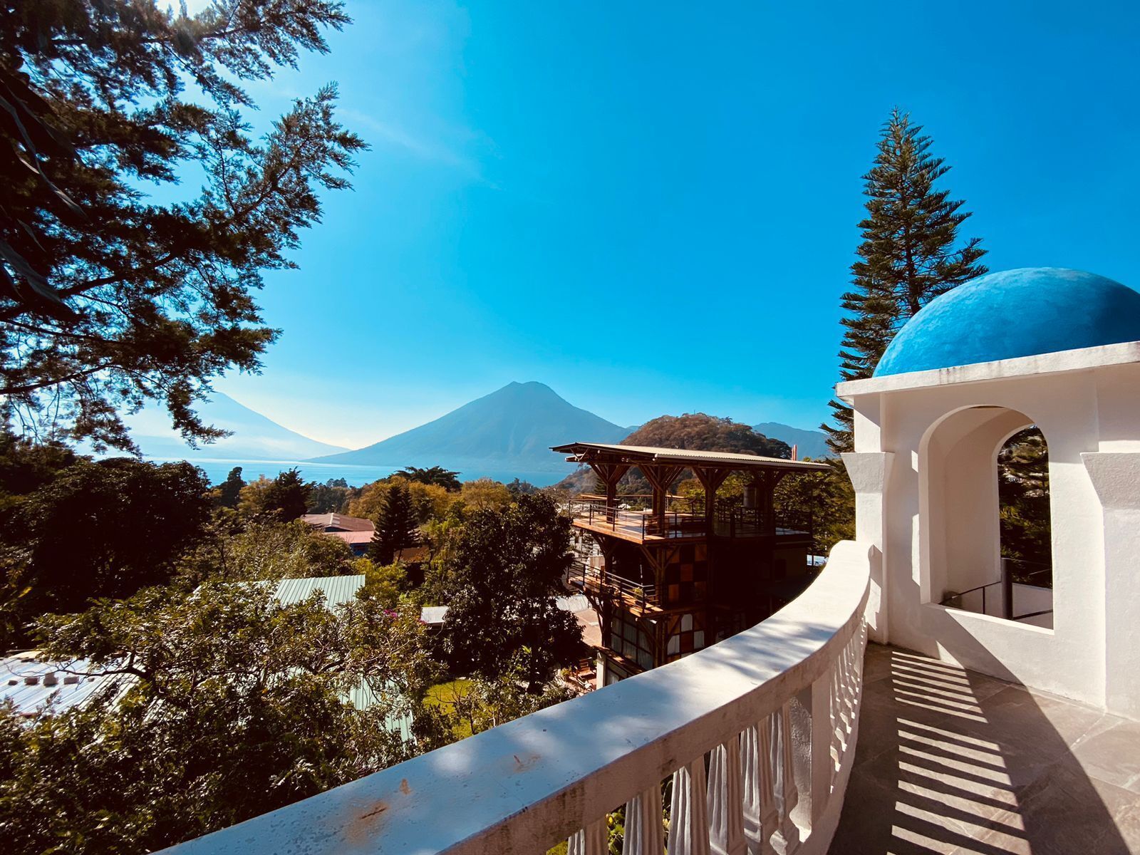 Une vue sur une montagne, avec un ciel dégagé, une structure en forme de dôme bleu et une végétation luxuriante tout autour.