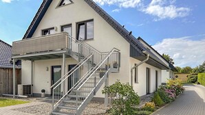 Ein modernes, zweistöckiges Gebäude mit Balkon, Treppe und Garten.