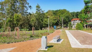 A paved pathway in a park with benches and trees. - Ferienwohnung Kölpinsee/Usedom (Kölpinsee/Usedom)