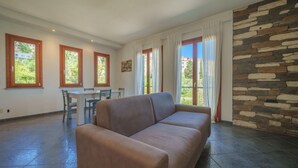 Un salon comprenant un canapé, une table à manger, des chaises et un mur en pierre.