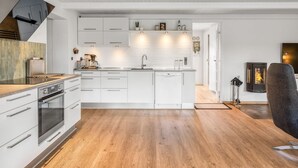 Et moderne køkken med hvide skabe, en indbygget ovn og en central ø.