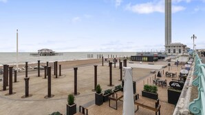 A coastal promenade with a monument, seating areas, and a pier in the background. - Coastal Sunset By My Getaways (Brighton)