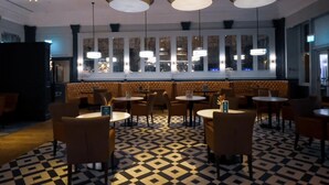 A restaurant with a patterned floor, round tables, and booths. - Coastal Sunset By My Getaways (Brighton)