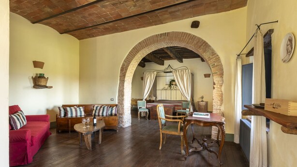 Una habitación acogedora con un banco de madera, un sofá rojo y una cama con dosel.