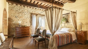 Un dormitorio rústico con pared de piedra, muebles de madera y una cama con dosel.