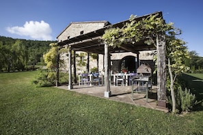 A stone building with a covered patio area, outdoor seating, and a view of the surrounding landscape.