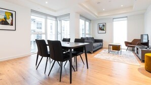 Ein modernes Wohnzimmer mit Essbereich, großen Fenstern und einem Flachbildfernseher.