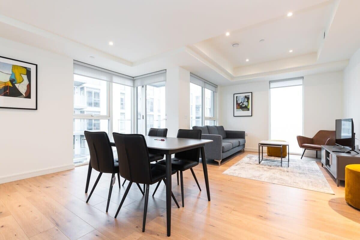 Un salon moderne comprenant un coin repas, de grandes fenêtres et un téléviseur à écran plat.