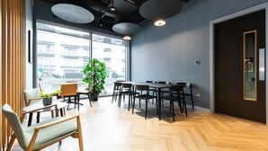 Une salle de conférence moderne, dotée d’une grande table, de chaises et d’une plante en pot.