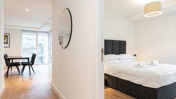A modern hotel room with a bed, bedside table, and a large window.