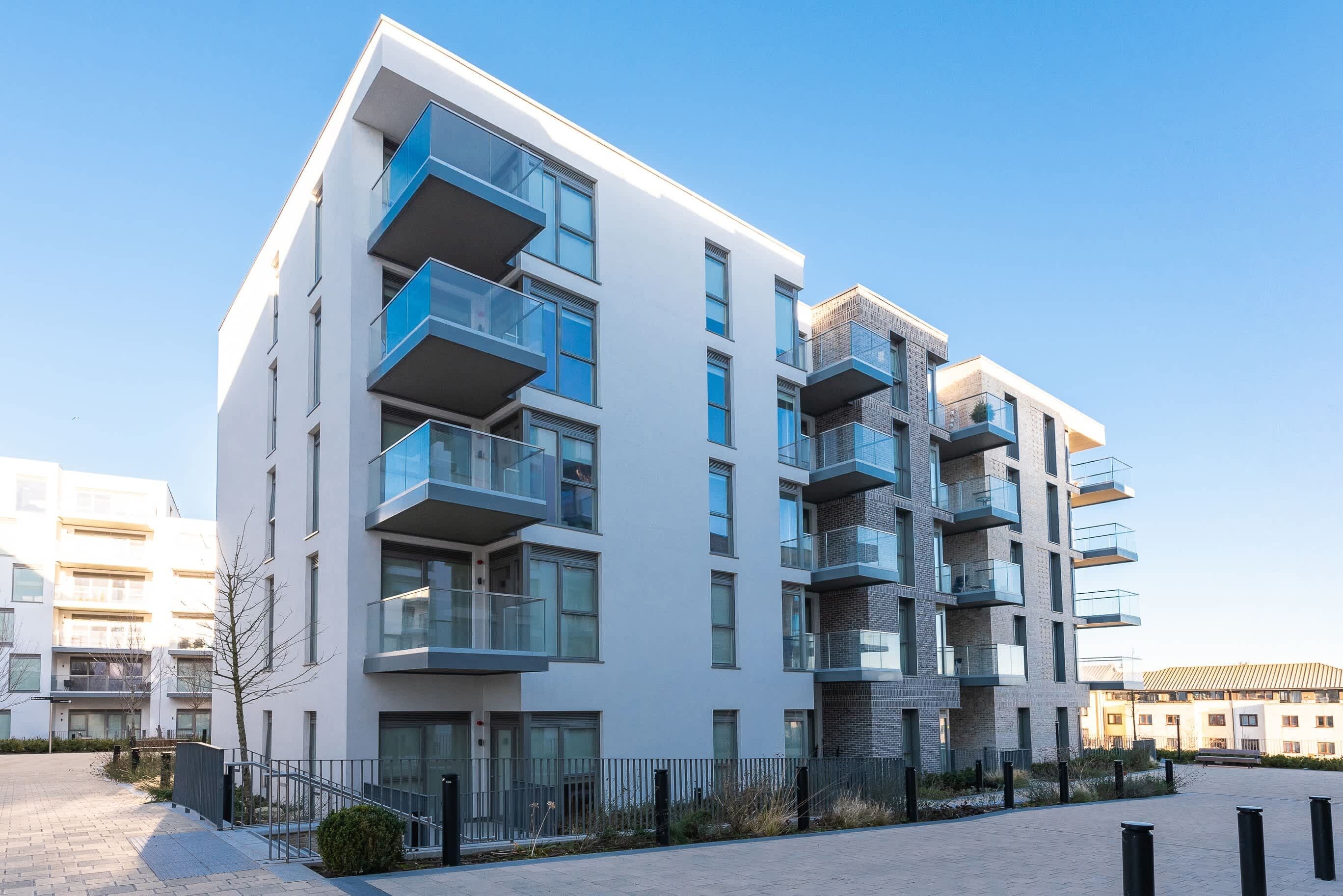 Een modern, meerlaags woongebouw met balkons, grote ramen en een strak, eigentijds ontwerp.
