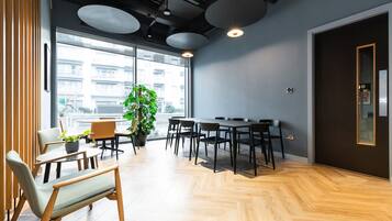 A modern meeting room with a large table, chairs, and a potted plant.