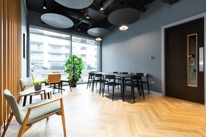 A modern meeting room with a large table, chairs, and a potted plant.