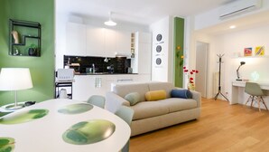 Una sala de estar moderna con un sofá, una mesa de comedor y una cocina al fondo.
