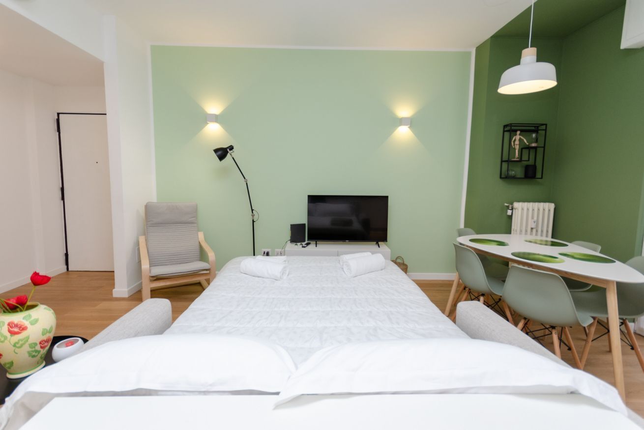 Una habitación de hotel con una cama, televisión, escritorio y una silla.