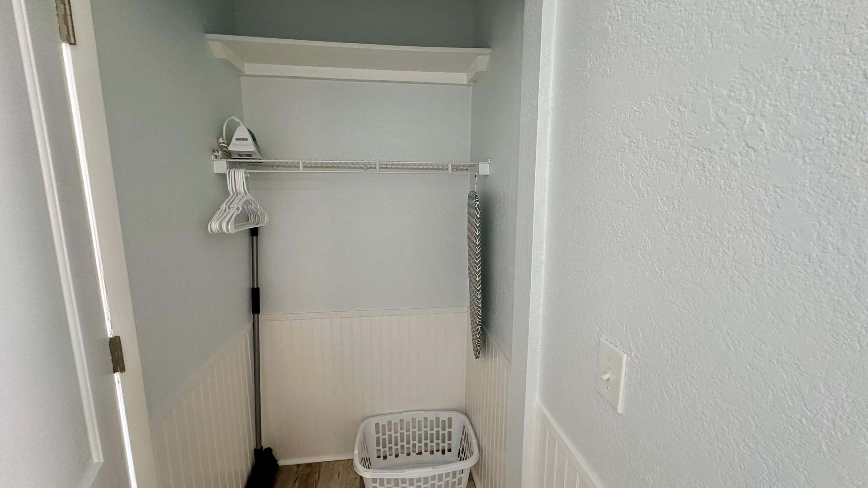Un área de lavandería con un tendedero, una cuerda para colgar ropa y una cesta de ropa.