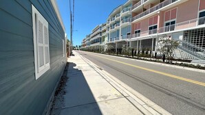 A multi-story hotel with balconies, a sidewalk, and a clear sky. - One Particular Cottage - Next to Margaritaville (Fort Myers Beach)