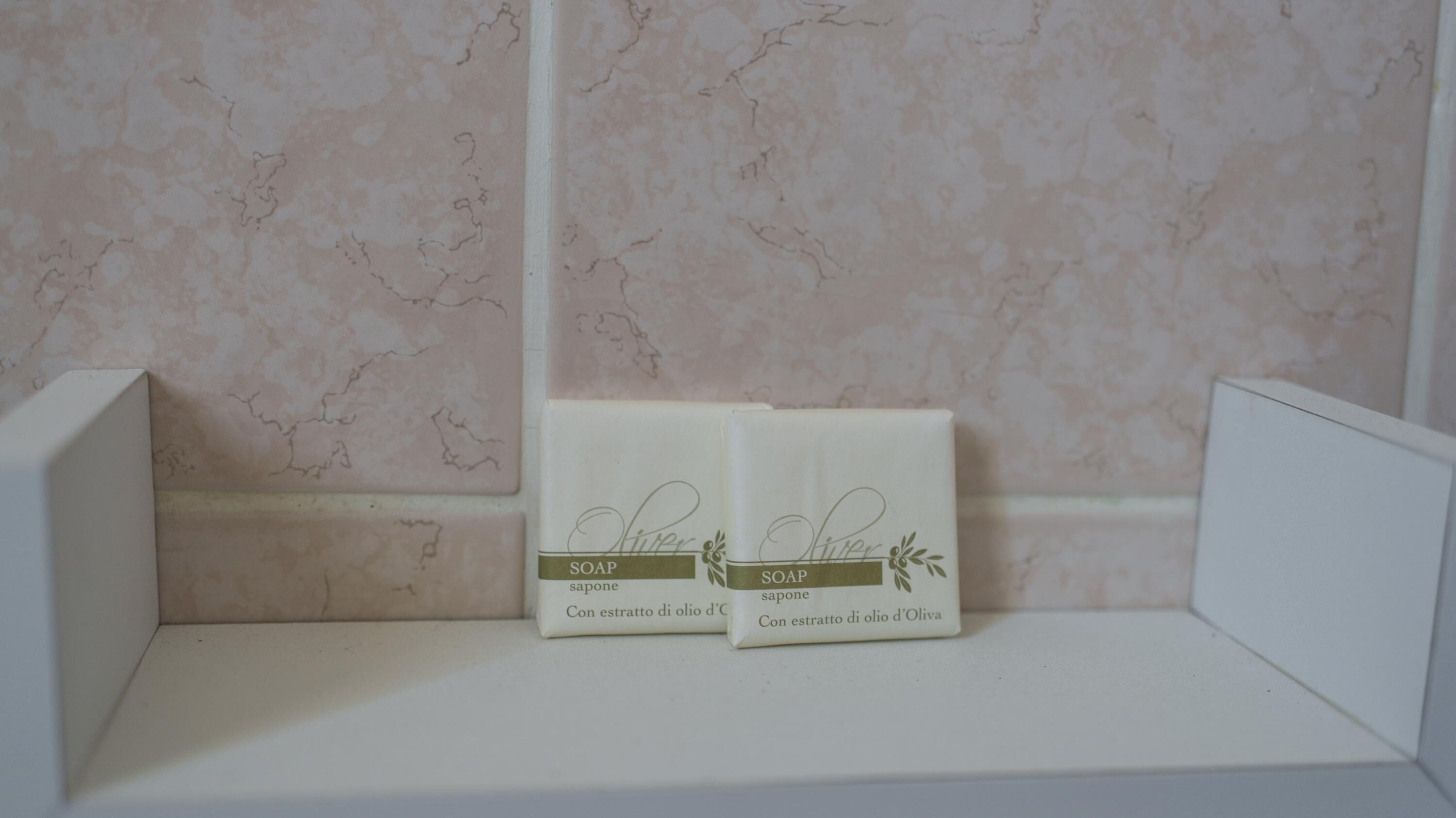 Two soap bars on a shelf with a marble wall background.