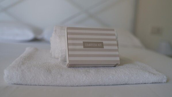 A neatly arranged toiletries kit on a white towel in a hotel room.