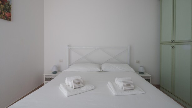 A minimalist bedroom with a bed, two nightstands, and a green wardrobe.