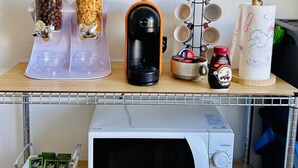 A kitchen counter with a microwave, coffee maker, and dispensers for coffee and sugar. - Casa Olbia Centro in Olbia (Olbia)