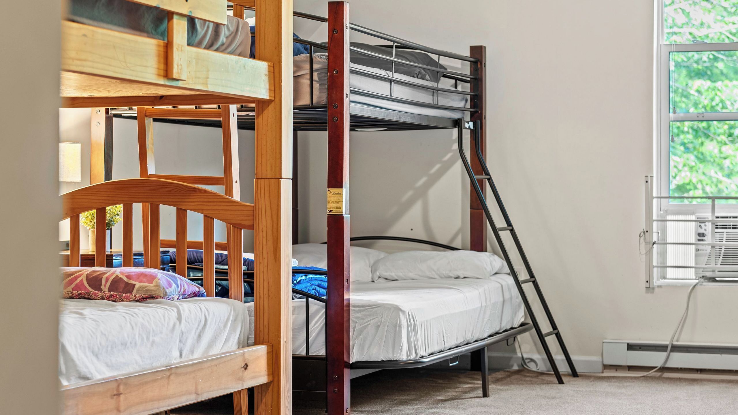Habitación con literas, ventana, radiador y una silla de madera.