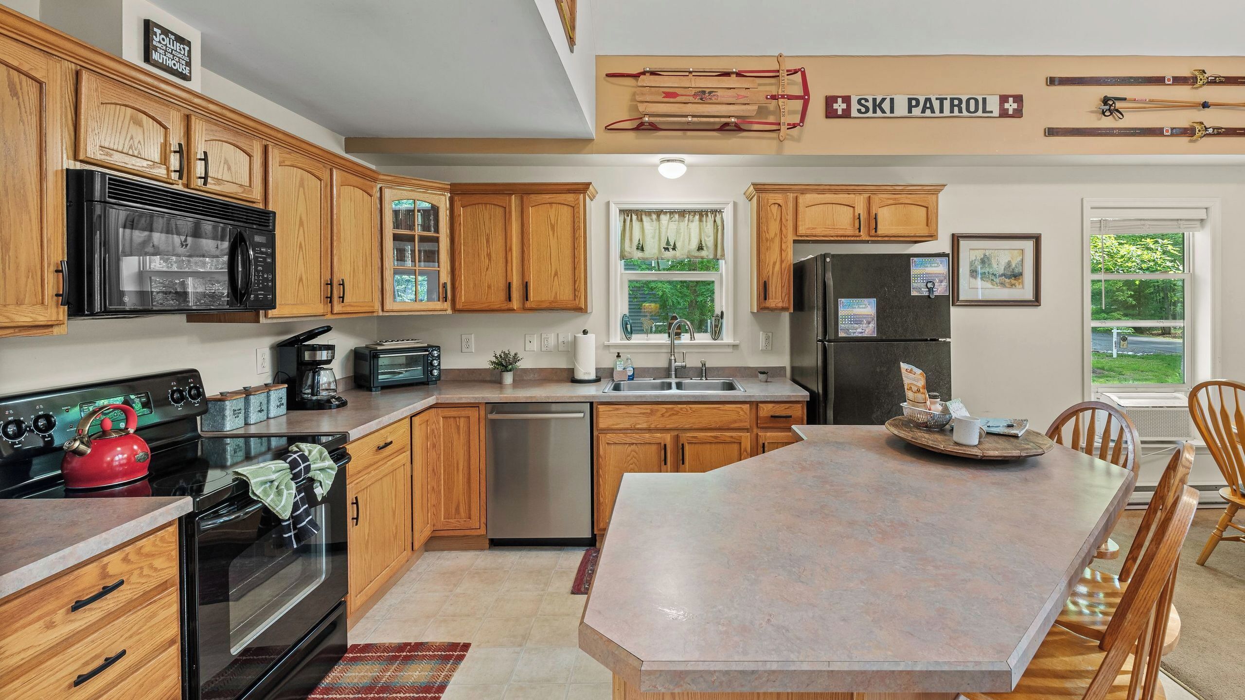 A kitchen with wooden cabinets, a stove, a refrigerator, and a dining area with a table and chairs.