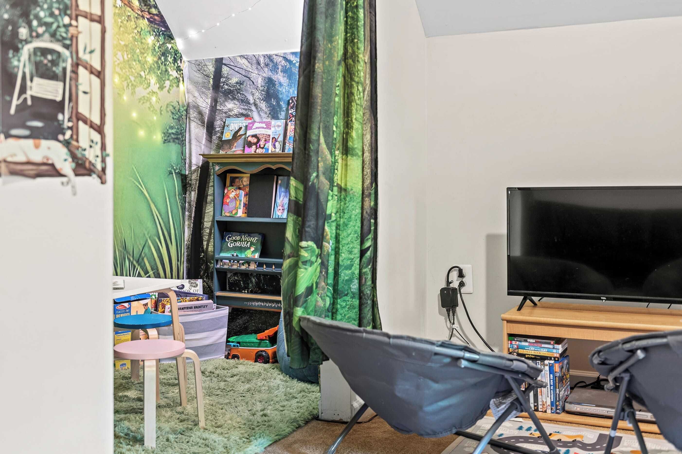 A cozy room with a TV, a bookshelf, and a chair.