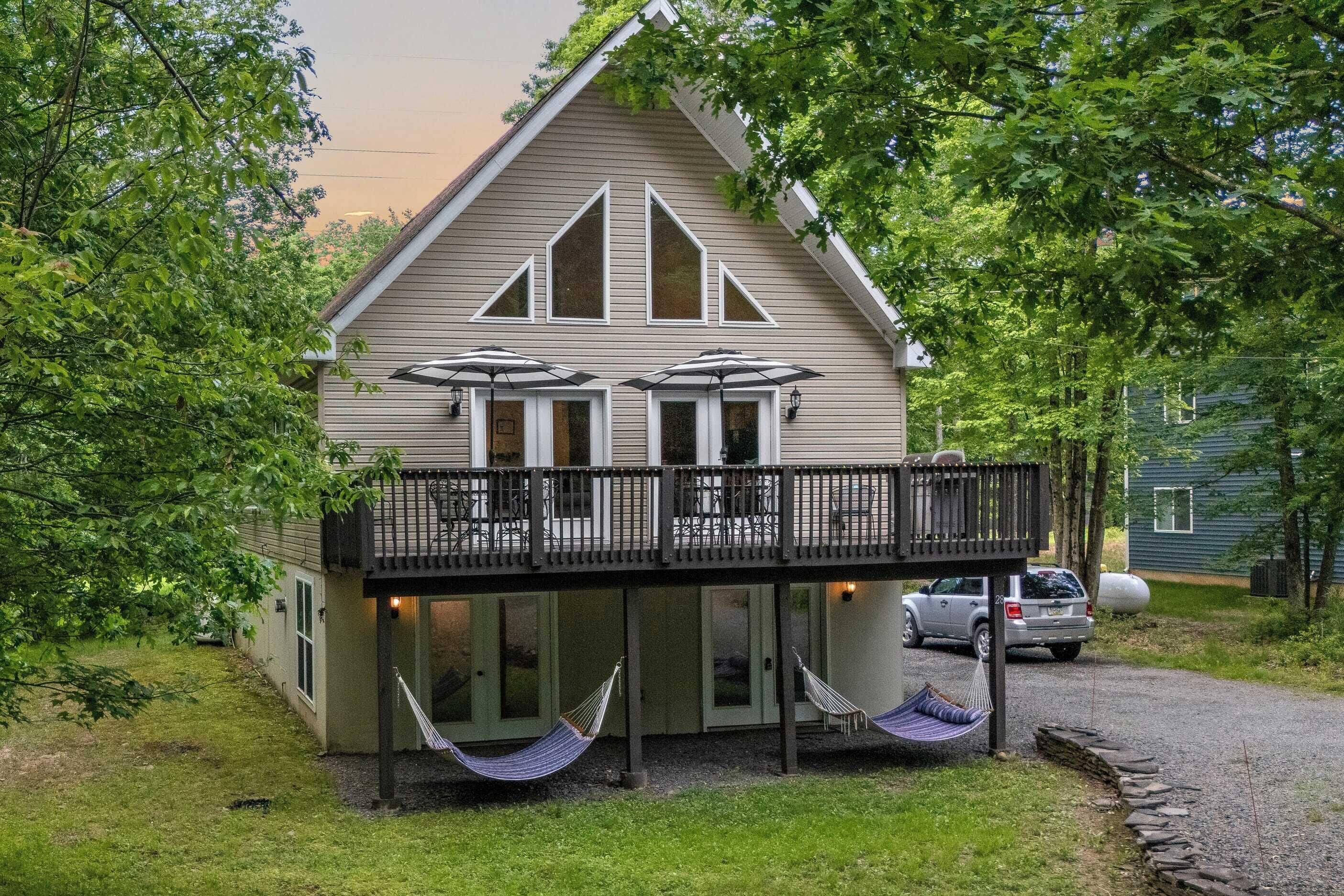 Et hus med balkon, bil parkeret i nærheden og en hængekøje.