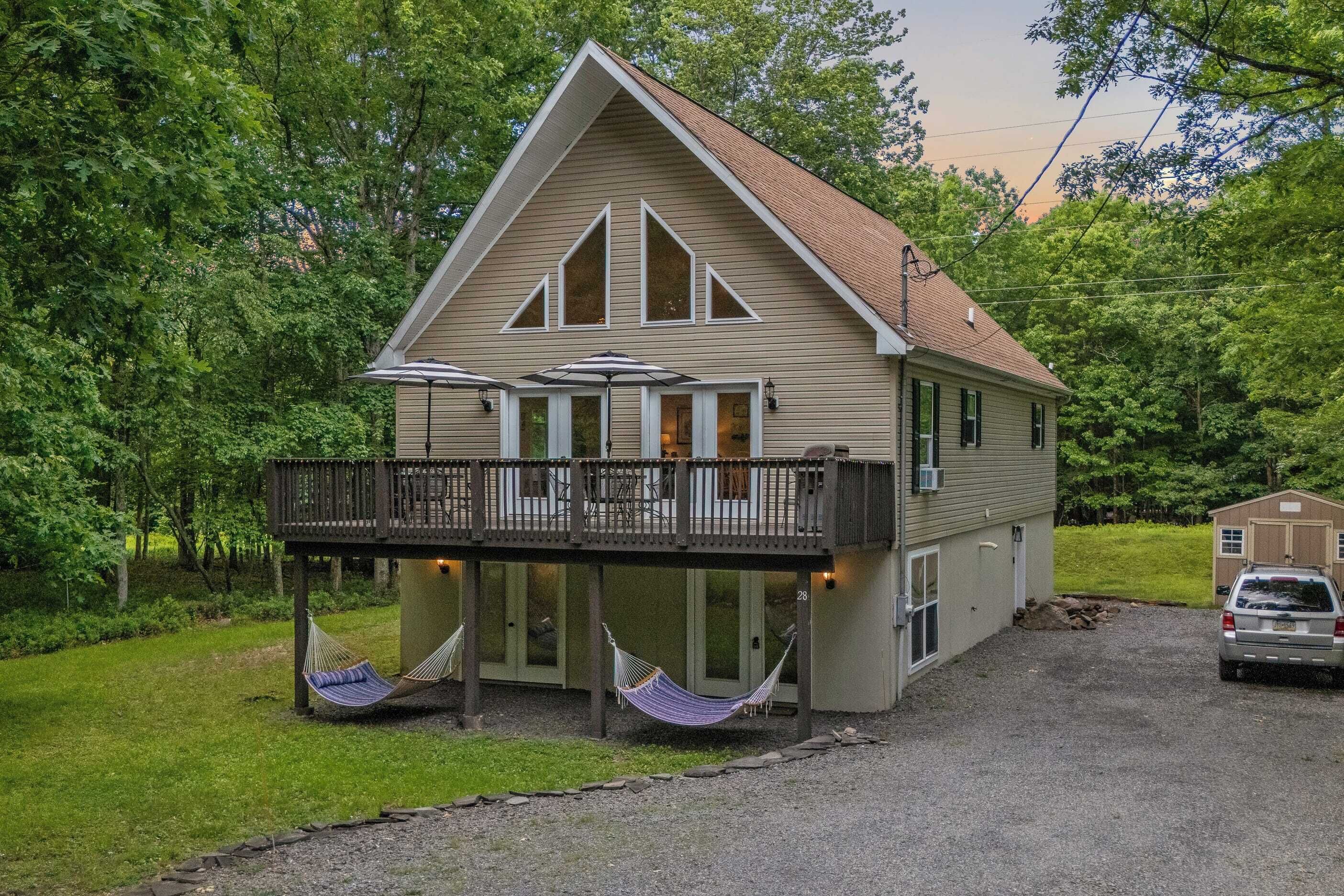 A two-story house with a balcony, a covered porch, and two hammocks.