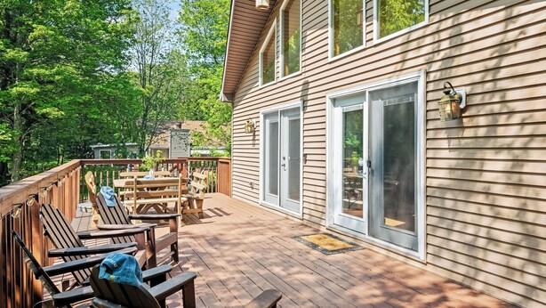A deck with outdoor furniture, a covered patio, and a house with large sliding glass doors. - Mews Mountain House by Avantstay Walk to Beach, Hot Tub, Game Room (Albrightsville)