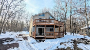 A two-story cabin with a balcony, surrounded by a snowy forest. - The Bear Foot Lodge by Avantstay Game Room, Deck, Beach/lake Access (Albrightsville)