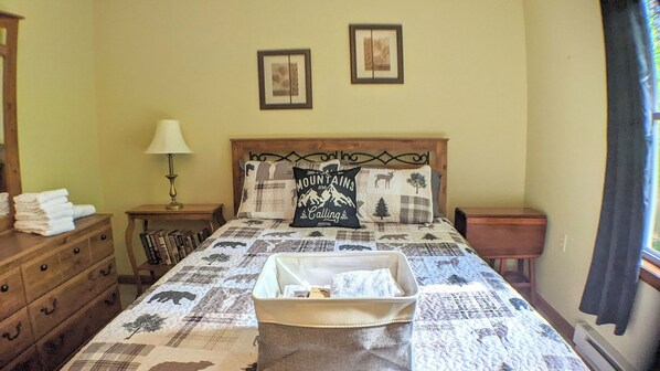 A bedroom with a bed, a nightstand, a dresser, and a lamp. - The Bear Foot Lodge by Avantstay Game Room, Deck, Beach/lake Access (Albrightsville)