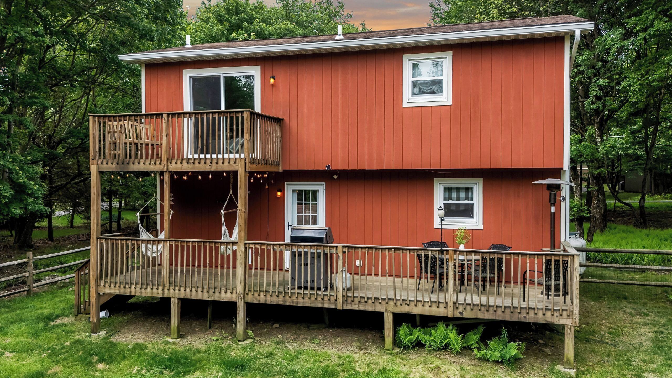 A two-story house with a balcony, a deck, and a small outdoor seating area.