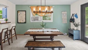 A dining area with a wooden table, bench, chairs, and a hanging light fixture.