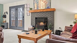 A living room with a fireplace, a wooden coffee table, a leather sofa, and a door leading to a balcony.