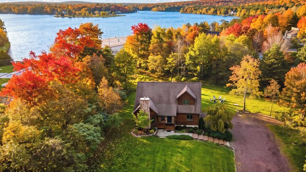 A single-story house with a stone foundation and a dark roof, surrounded by a well-maintained lawn and a driveway. - Entertainer's Home w/ Deck, Game Room & Hot Tub Lake View Retreat by Avantstay (Albrightsville)