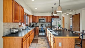 A spacious kitchen with wooden cabinets, stainless steel appliances, and pendant lighting.