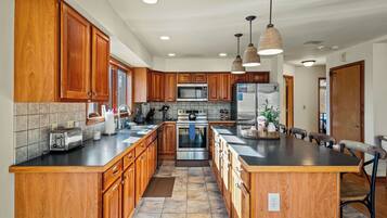 A spacious kitchen with wooden cabinets, stainless steel appliances, and pendant lighting.