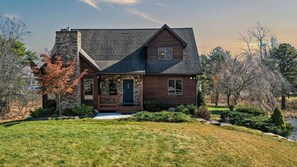 A two-story house with a stone chimney, a front porch, and a well-maintained lawn. - Entertainer's Home w/ Deck, Game Room & Hot Tub Lake View Retreat by Avantstay (Albrightsville)