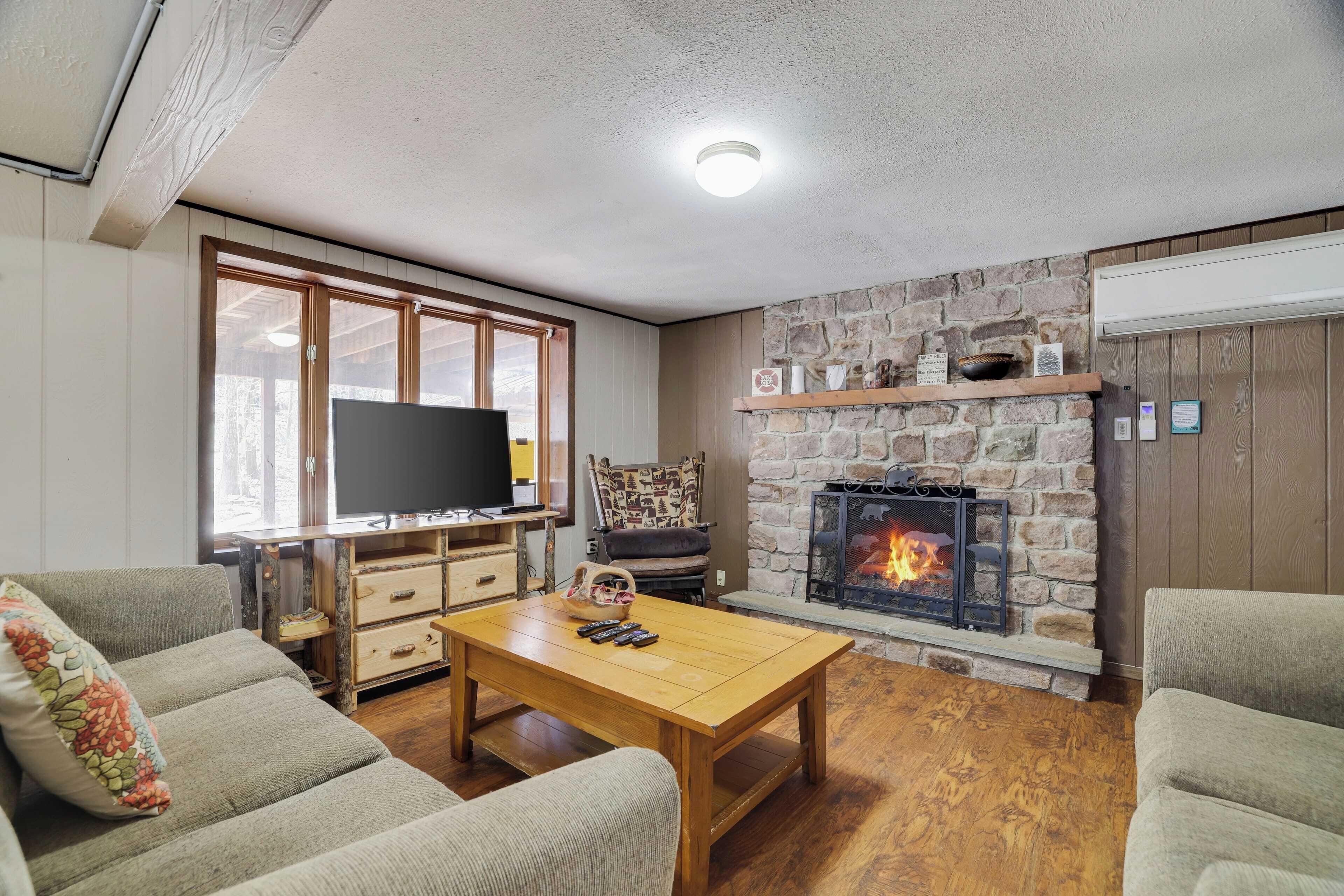 A living room with a stone fireplace, wooden furniture, and a television.