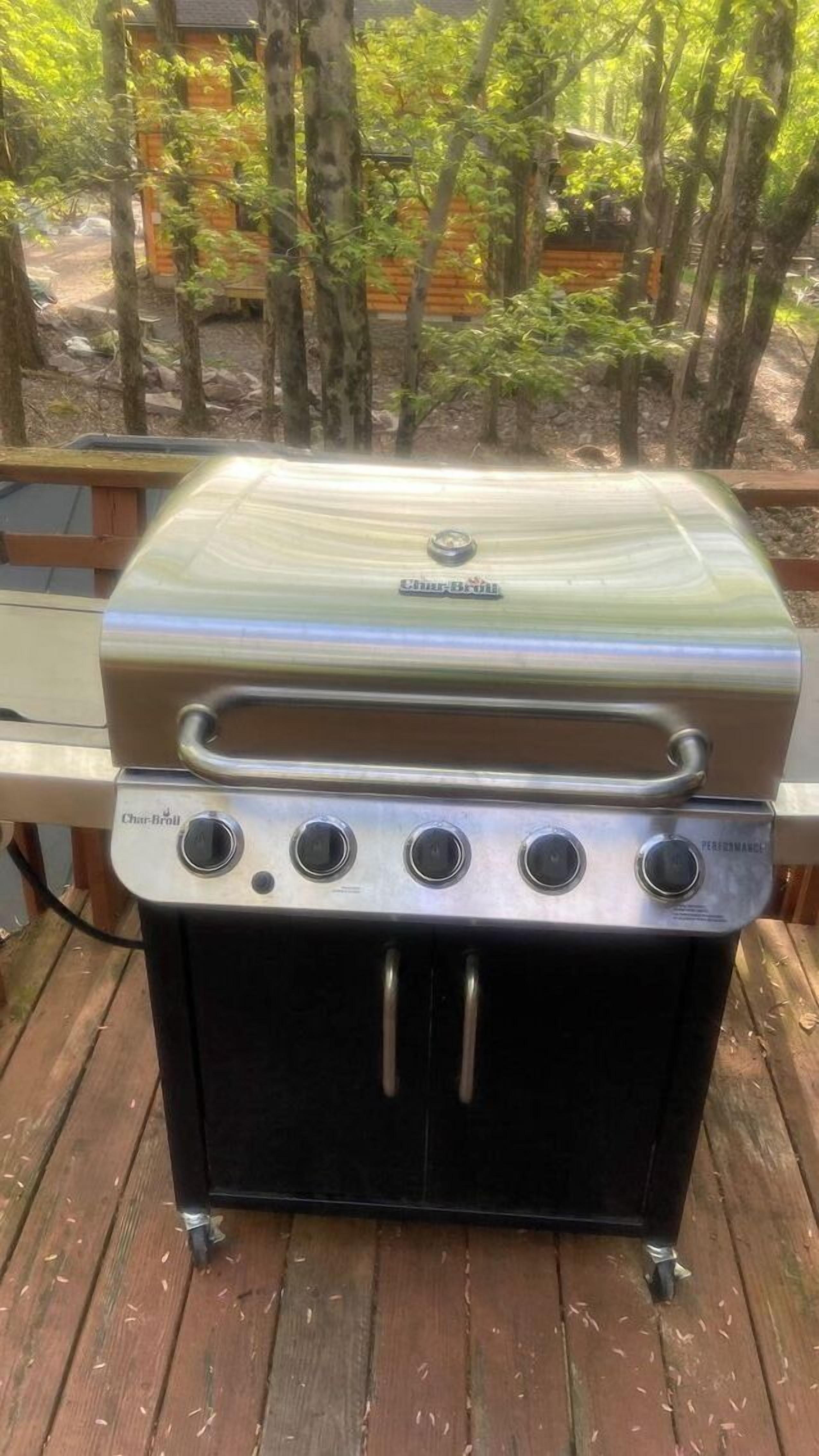 Een Char-Broil gasgrill met vier branders, een bijbehorend plankje en een scharnierend deksel.