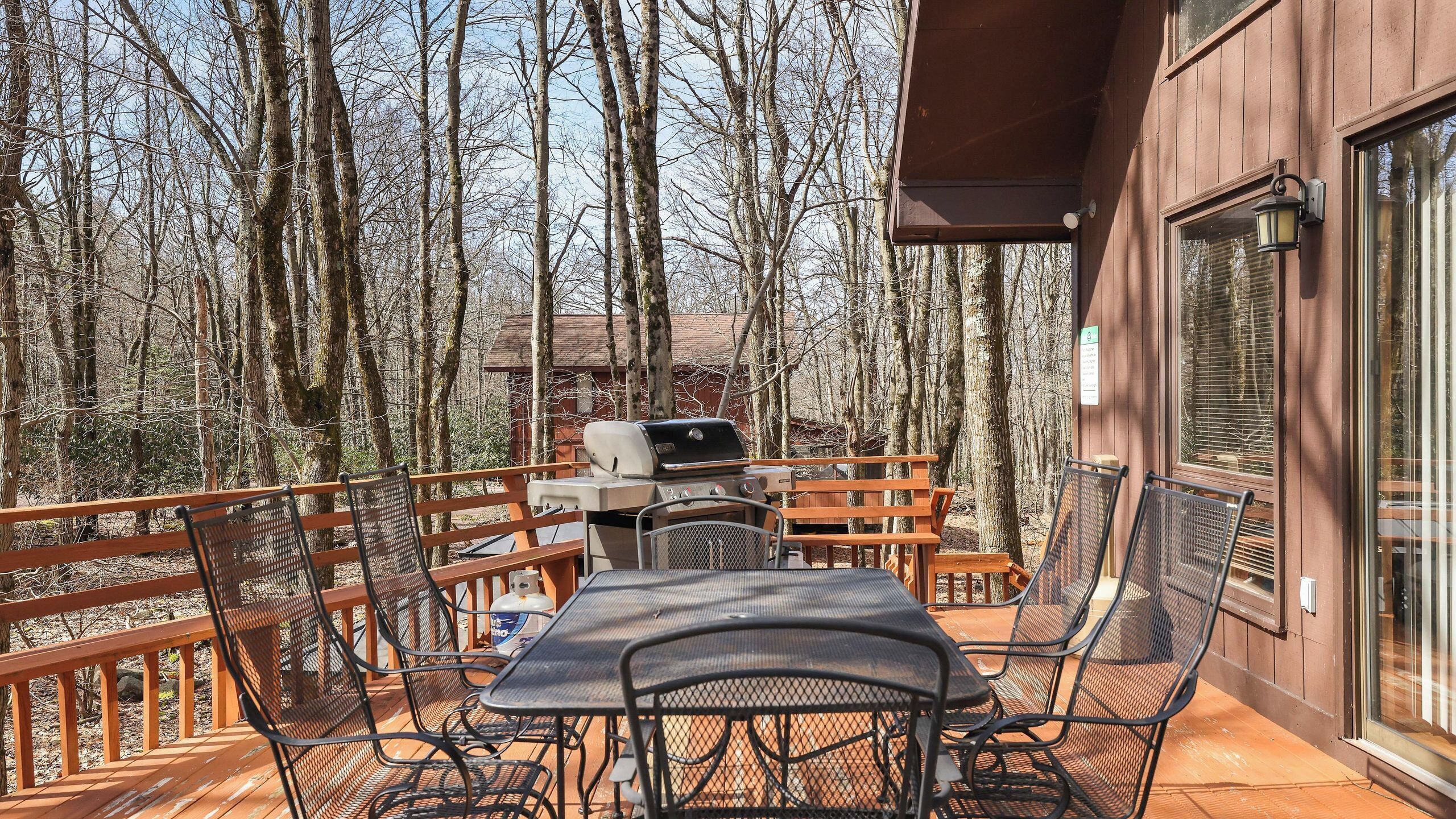 Eine Terrasse mit Grill, Stühlen und einem Tisch.