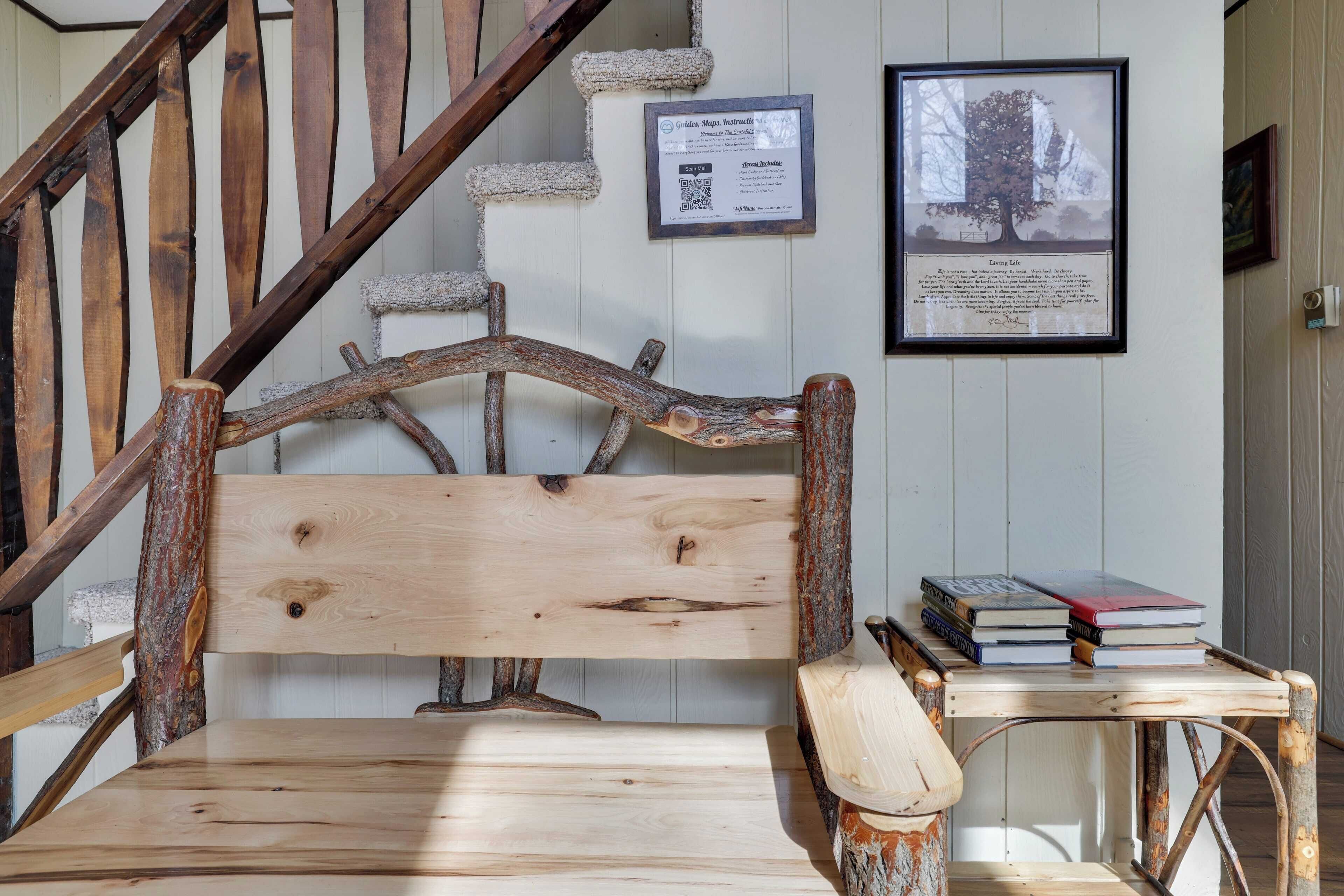 Une chaise et une table en bois rustique se trouvent dans une pièce dotée d’un escalier en bois et d’une plaque d’information encadrée accrochée au mur.