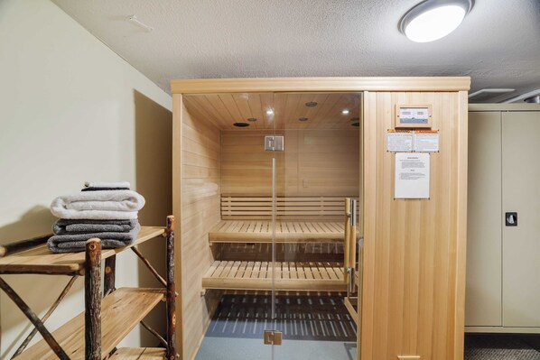 A sauna with wooden benches and a glass door, a towel rack, and a control panel on the wall. - Hot Tub + Sauna + Deck + Firepit + Beach Access + Near Dining Grateful Escape by Avantstay (Lake Harmony)