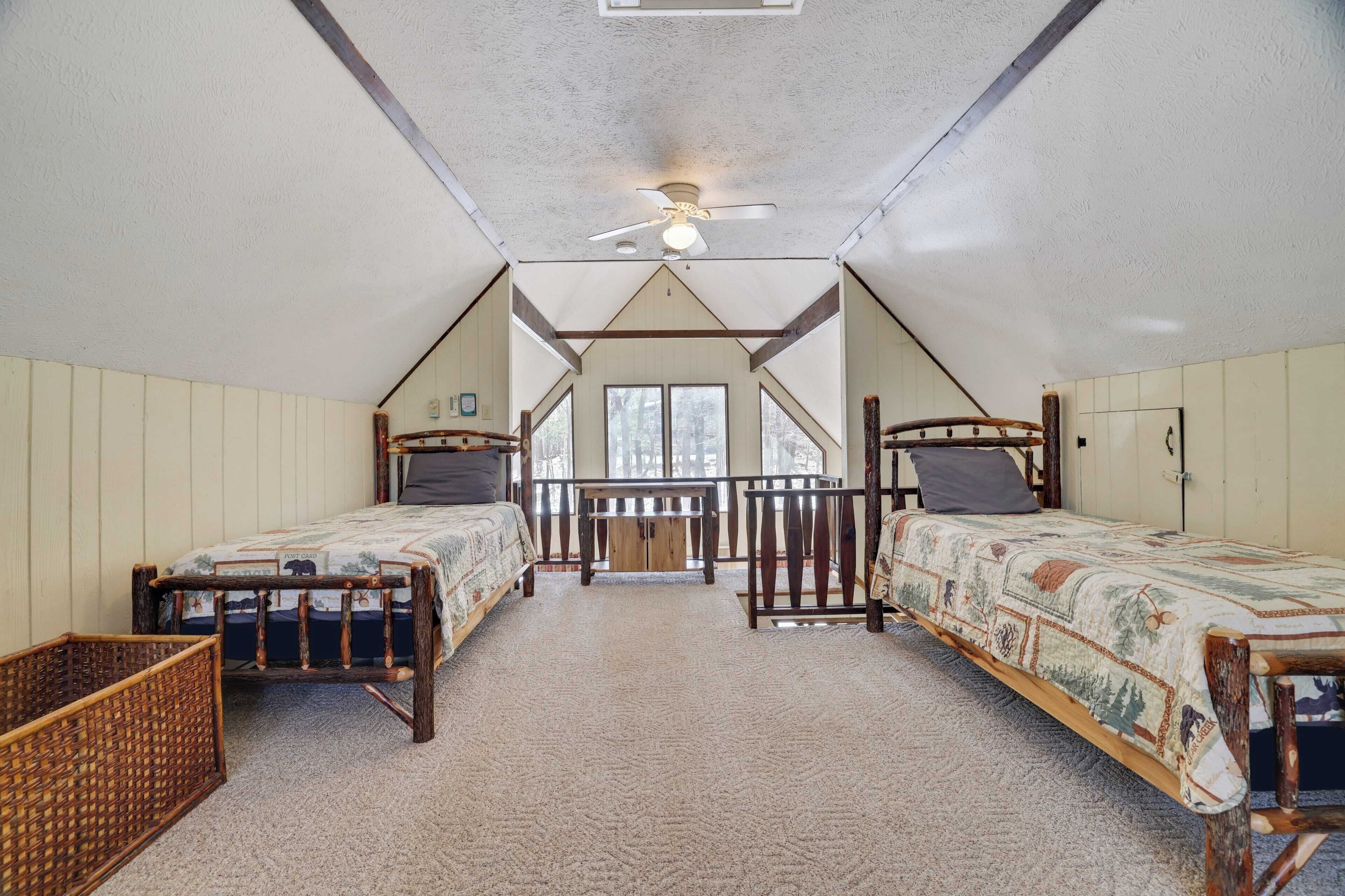 Quarto com duas camas de madeira, um ventilador de teto e vista do exterior através de grandes janelas.