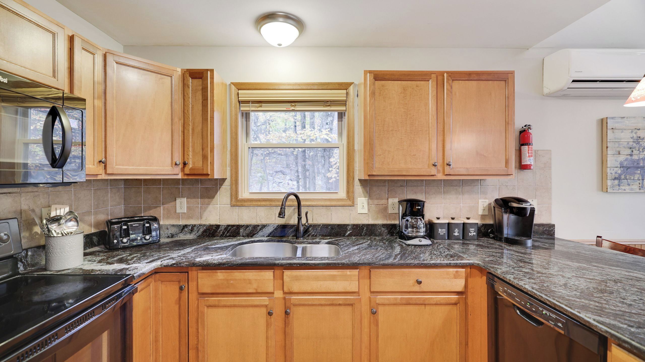A kitchen with wooden cabinets, a stainless steel sink, a coffee maker, and a toaster.